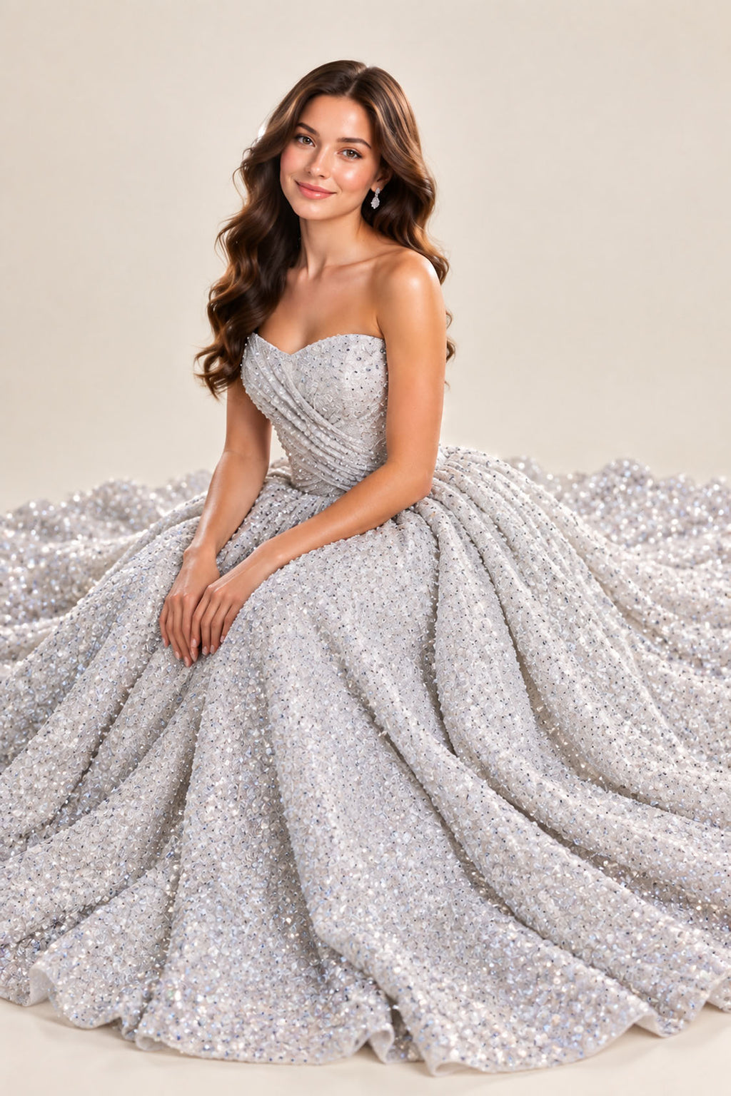 Silver glitter tulle strapless ball gown prom dress with skirt spread around the model, seated pose